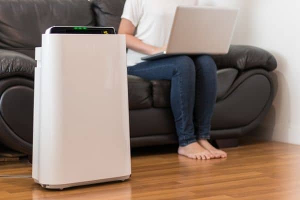 Air purifier on floor next to person improves air quality