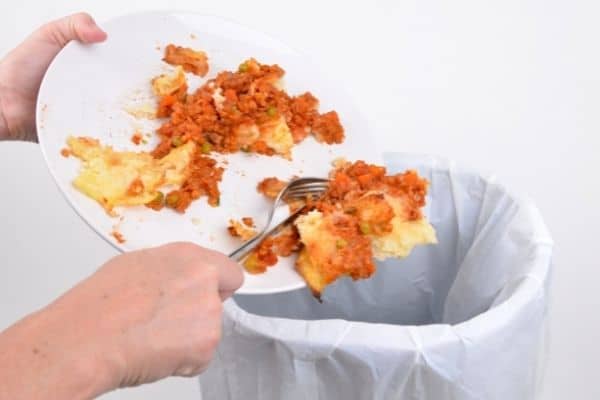 Person scraping food into bin