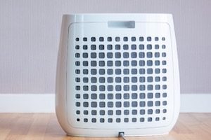 Air purifier on floor by purple wall